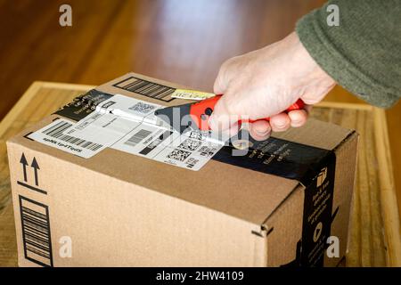 Ouverture d'une boîte en carton à l'aide d'un couteau universel. Banque D'Images