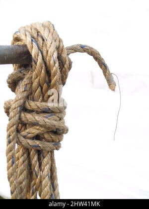 Corde enroulée accrochée sur un tuyau isolé sur la whiite Banque D'Images