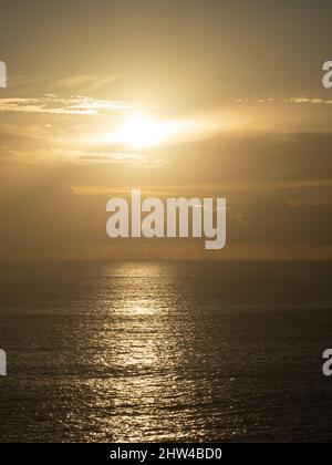 Lever du soleil sur l'océan Pacifique, soleil doré brillant à travers les nuages dans le ciel sombre, poutres et rayons reflétés l'or sur la mer, côte de Nouvelle-Galles du Sud Australie Banque D'Images