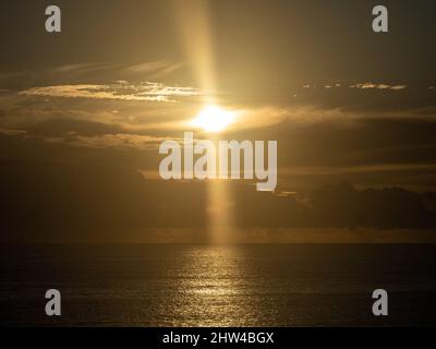 Lever du soleil sur l'océan Pacifique, soleil doré brillant à travers les nuages dans le ciel sombre, poutres et rayons reflétés l'or sur la mer, côte de Nouvelle-Galles du Sud Australie Banque D'Images