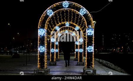 Arches décorées de guirlandes dans le parc de la ville. Concept. Les gens passent par des arches avec des guirlandes. Les gens marchent sous des arches décorées avec des guirlandes glowi Banque D'Images