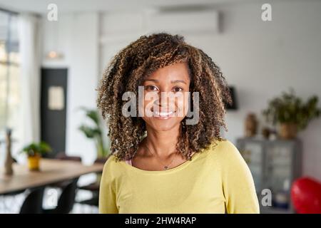 Portrait d'une belle jeune femme adulte souriant. Fille africaine en décontracté regardant l'appareil photo avec. Course mixte et gaie se détendre à la maison avec grand rire. Banque D'Images