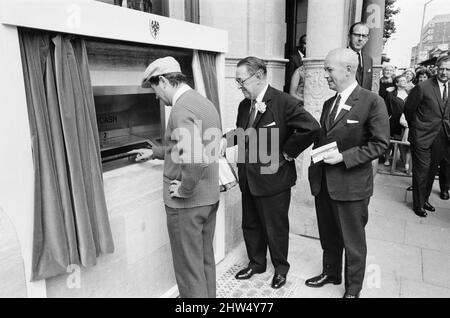 Le premier guichet automatique de Worlds, Cash machine, est dévoilé à la Barclays Bank, à Enfield, Middlesex, juste au nord de Londres. 27th juin 1967. La photo montre l'acteur Reg Varney dans sa casquette blanche. Barclays ATM, 27th juin 1967. Sir Thomas Bland, vice-président de Barclays Bank, dévoile un robot de caisse qui distribue de l'argent à tout moment du jour ou de la nuit. Conçue et développée conjointement avec de la rue instruments et le service des services de gestion des banques, la machine BarclayCash est installée dans la succursale d'Enfield. L'acteur Reg Varney a pris le temps de filmer la série télévisée « Beggar Your Neighbor » à Northwood à Banque D'Images