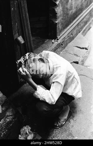 La vie en 1960s à Hong Kong, ville coloniale, avec une population en croissance rapide de plus de 4 millions de personnes, beaucoup sont forcés de vivre dans des cabanes et des bidonvilles de squatter, illustrés en janvier 1968. Notre photo montre ... enfant lave les cheveux au-dessus de drain. Banque D'Images