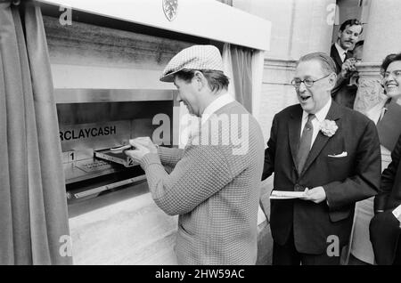 Le premier guichet automatique de Worlds, Cash machine, est dévoilé à la Barclays Bank, à Enfield, Middlesex, juste au nord de Londres. 27th juin 1967. La photo montre l'acteur Reg Varney dans sa casquette blanche. Barclays ATM, 27th juin 1967. Sir Thomas Bland, vice-président de Barclays Bank, dévoile un robot de caisse qui distribue de l'argent à tout moment du jour ou de la nuit. Conçue et développée conjointement avec de la rue instruments et le service des services de gestion des banques, la machine BarclayCash est installée dans la succursale d'Enfield. L'acteur Reg Varney a pris le temps de filmer la série télévisée « Beggar Your Neighbor » à Northwood à Banque D'Images