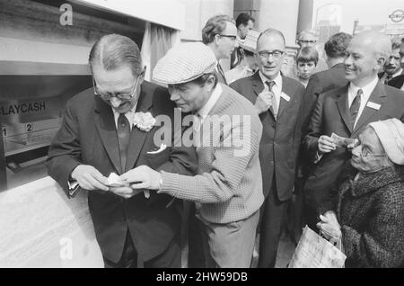 Le premier guichet automatique de Worlds, Cash machine, est dévoilé à la Barclays Bank, à Enfield, Middlesex, juste au nord de Londres. 27th juin 1967. La photo montre l'acteur Reg Varney dans sa casquette blanche. Barclays ATM, 27th juin 1967. Sir Thomas Bland, vice-président de Barclays Bank, dévoile un robot de caisse qui distribue de l'argent à tout moment du jour ou de la nuit. Conçue et développée conjointement avec de la rue instruments et le service des services de gestion des banques, la machine BarclayCash est installée dans la succursale d'Enfield. L'acteur Reg Varney a pris le temps de filmer la série télévisée « Beggar Your Neighbor » à Northwood à Banque D'Images