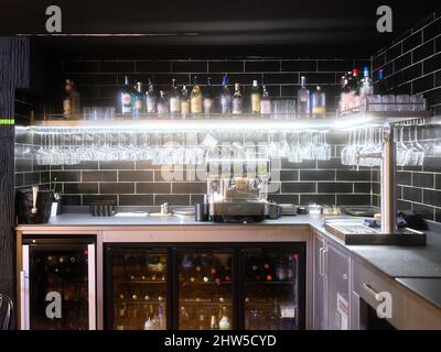 Restaurant avec des verres suspendus à un porte-bouteilles et des bouteilles de vin dans le réfrigérateur Banque D'Images