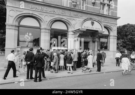 Le premier guichet automatique de Worlds, Cash machine, est dévoilé à la Barclays Bank, à Enfield, Middlesex, juste au nord de Londres. 27th juin 1967. La photo montre la foule de clients et de spectateurs locaux, voyant le premier guichet automatique au monde travailler pour la première fois. Barclays ATM, 27th juin 1967. Sir Thomas Bland, vice-président de Barclays Bank, dévoile un robot de caisse qui distribue de l'argent à tout moment du jour ou de la nuit. Conçue et développée conjointement avec de la rue instruments et le service des services de gestion des banques, la machine BarclayCash est installée dans la succursale d'Enfield. L'acteur Reg Varney a pris le temps de quitter Filmi Banque D'Images