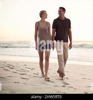 Ils aiment les longues promenades sur la plage. Photo d'un couple mature qui fait une promenade sur la plage. Banque D'Images