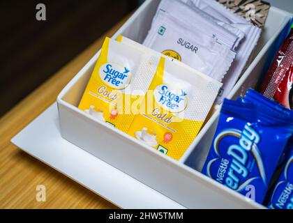 Mise au point sélective de deux paquets d'édulcorants artificiels d'or sans sucre dans un rack en plastique blanc. Banque D'Images