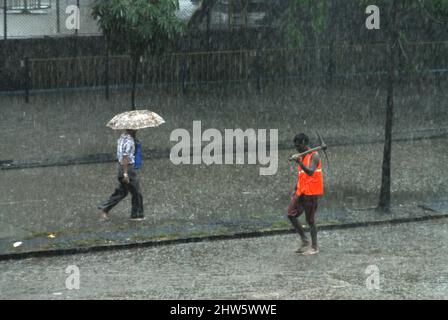 Mumbai, Maharashtra, Inde-Asie, juin 2007 : les gens qui marchent à travers la voie ferrée inondée de bûcher de l'eau lors de fortes pluies à Parel Mumbai Banque D'Images