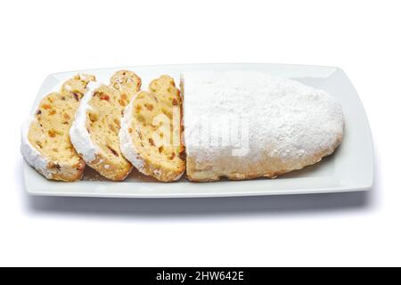 Gâteau de Noël traditionnel en tranches avec massepain et fruits secs isolés sur une plaque en céramique Banque D'Images