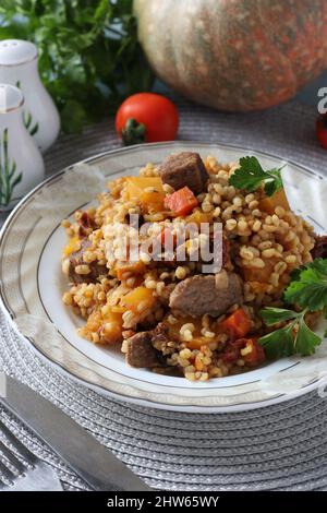 Bœuf avec boulgour et légumes tels que la citrouille, les carottes, les oignons et les tomates séchées, format vertical Banque D'Images