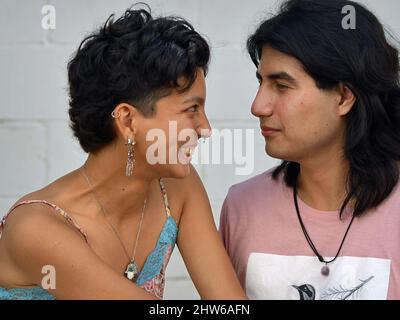 Une belle femme mexicaine jeune et souriante Latina et un beau sérieux mexicain jeune Latino homme sont amoureux et regardent dans les yeux de l'autre. Banque D'Images