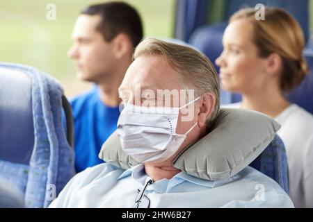 homme âgé en masque dormant dans un bus de voyage Banque D'Images