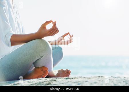 La paix des natures absorbantes. Une jeune femme effectuant une routine de yoga sur la plage sous le soleil d'été. Banque D'Images