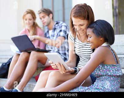 Les adolescents technologiques. Les jeunes adolescents regardent leurs ordinateurs portables et leurs tablettes numériques pendant qu'ils socialisent à l'extérieur. Banque D'Images