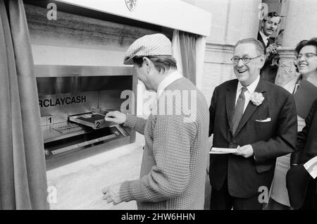 Le premier guichet automatique de Worlds, Cash machine, est dévoilé à la Barclays Bank, à Enfield, Middlesex, juste au nord de Londres. 27th juin 1967. La photo montre l'acteur Reg Varney dans sa casquette blanche. Barclays ATM, 27th juin 1967. Sir Thomas Bland, vice-président de Barclays Bank, dévoile un robot de caisse qui distribue de l'argent à tout moment du jour ou de la nuit. Conçue et développée conjointement avec de la rue instruments et le service des services de gestion des banques, la machine BarclayCash est installée dans la succursale d'Enfield. L'acteur Reg Varney a pris le temps de filmer la série télévisée « Beggar Your Neighbor » à Northwood à Banque D'Images