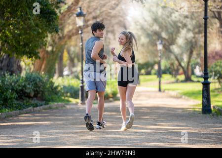 Un jeune couple fait du sport sur un sentier de parc et regarde la caméra Banque D'Images