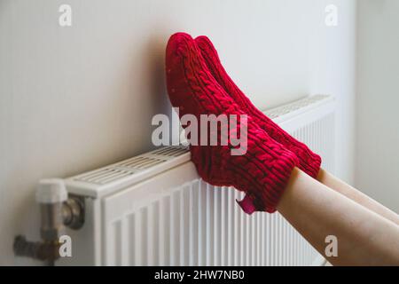 Une jeune femme en chaussettes chaudes et confortables réchauffe ses jambes près de la Banque D'Images