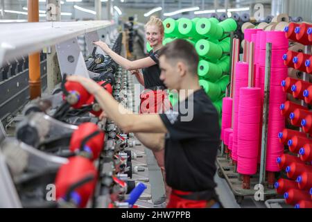 01 mars 2022, Saxe, Flöha: Deux employés changent de bobines avec des fils de couleur dans le département de bobinage de l'OTEX Textilveredlung GmbH. La société, qui compte 90 employés, fabrique des fils spécialisés pour les produits médicaux et les textiles techniques. Lorsqu'un successeur de l'usine a été recherché en 2016, la société Thuringe Bauerfeind AG, fabricant d'aides médicales telles que des bandages, des orthèses ou des semelles intérieures orthopédiques, a simplement repris son fournisseur lui-même. Le nombre d'employés a augmenté, et maintenant plusieurs Roumains et Sud-Américains font également partie de la main-d'œuvre. Photo: Jan Woitas/dpa-Zentralbild/ZB Banque D'Images