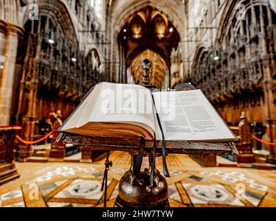 Une bible repose sur un vieux pupitre en bois ouvert sur 1 Corinthiens dans le Quire à la cathédrale de Chester. Banque D'Images