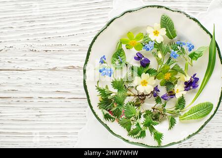 Ingrédients alimentaires de plantes de printemps sains. Pissenlit, ail sauvage, fleurs et ortie sur l'assiette Banque D'Images