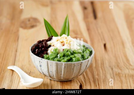 Desserts malaisiens et de Singapour appelés Cendol. Le Cendol est fait à partir de cubes de glace écrasés, de haricots rouges, d'une variété de sucreries et de fruits. Sur une table en bois Banque D'Images