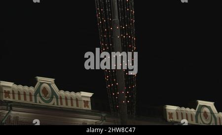Vue de dessous de nombreuses petites ampoules clignotantes. Guirlande de rue festive s'étire contre le ciel de nuit noire, concept de Noël et du nouvel an. Banque D'Images