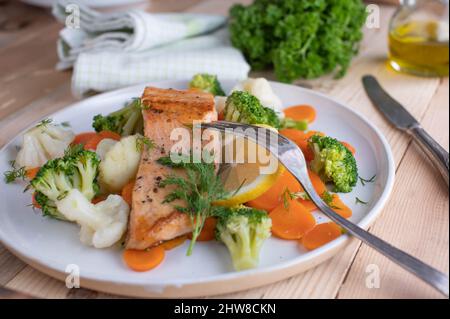 Plat de poisson sain avec filet de saumon poêlé servi avec des légumes impériaux comme le brocoli, le chou-fleur et les carottes sur une assiette. Dîner au buffet bas Banque D'Images