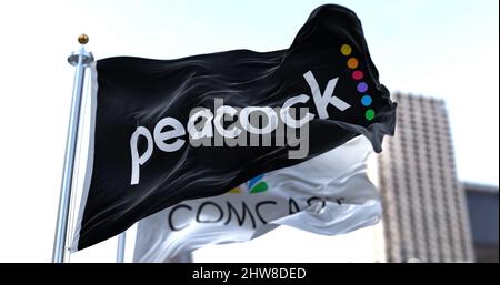 New York, Etats-Unis, janvier 2022: Drapeau de Peacock TV agitant dans le vent avec le drapeau Comcast en arrière-plan. Peacock est un utilisateur américain de streaming vidéo Banque D'Images