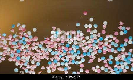 Gros plan de saupoudrer en forme de cœur. Concept. Vue de dessous de verre transparent avec des arrosés multicolores éparpillés dessus. Saupoudrer de plusieurs couleurs Banque D'Images