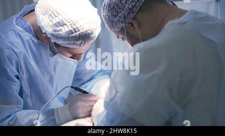 Les chirurgiens opèrent sur une personne sous anesthésie. Action. Deux chirurgiens professionnels font des incisions au patient sous anesthésie. Faces concentrées de la surtension Banque D'Images