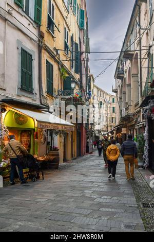 Une ruelle étroite dans la vieille ville de Sanremo avec des touristes marchant dans un ciel nuageux jour d'hiver, province d'Imperia, Ligurie, Italie Banque D'Images