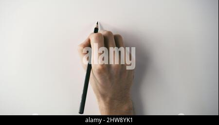 Main tenant un crayon noir sur une surface blanche prête à dessiner Banque D'Images