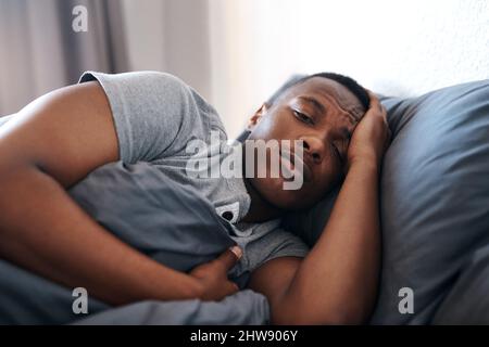 Je pense que je n'ai rien à faire ici toute la journée. Plan court d'un jeune homme beau allongé dans le lit et se sentant déprimé alors qu'il était à la maison seule. Banque D'Images