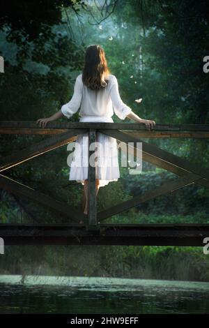 une femme en vêtements blancs se tient sur un pont dans un endroit magnifique et fabuleux Banque D'Images