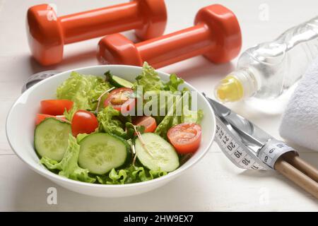 Bol de salade saine sur fond de bois clair, gros plan Banque D'Images