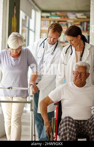 Les aînés en déplacement... avec une aide qui est. Photo d'une équipe de médecins aidant leurs patients âgés souffrant de déficiences physiques. Banque D'Images