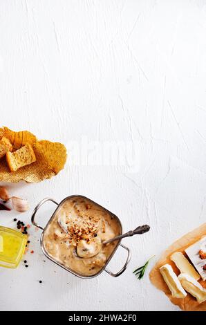 Faire fondre le cambre dans une casserole avec des champignons, du basilic et des croûtons à l'ail, sur une table en bois de style rustique Banque D'Images