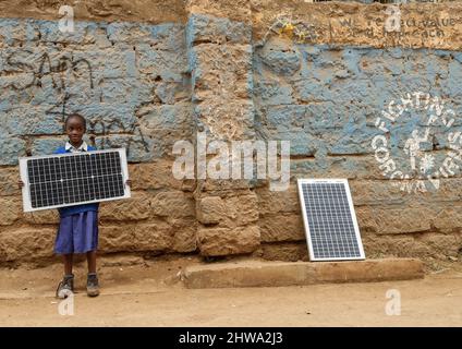 Nairobi, Kenya. 25th févr. 2022. Une jeune fille d'école vu porter un panneau solaire par les rues à Kibera.in Kibera bidonvilles, la plupart des résidents en particulier les vendeurs de rue, les écoles privées, les organisations non gouvernementales, les lumières de rue et les écoles utilisent tous le système d'énergie solaire bon marché qui est une source d'énergie plus fiable et bon marché. Cela a facilité le recyclage de la plupart de l'énergie électrique consommée par les résidents et a également contribué à réduire le nombre élevé de décès dus aux chocs électriques et aux incendies de taudis quotidiens. (Credit image: © Donwilson Odhiambo/SOPA Imag Banque D'Images
