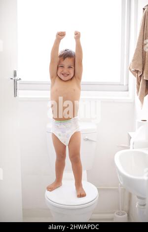 Je suis un grand gamin. Photo d'un jeune garçon heureux dans une couche debout sur un siège de toilette. Banque D'Images