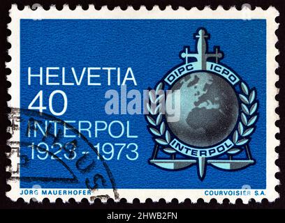 SUISSE - VERS 1973 : un timbre imprimé en Suisse montre l'emblème d'Interpol, vers 1973. Banque D'Images