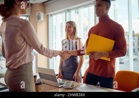 Une jeune commission est en train de prendre la main avec une candidate dans une atmosphère agréable après un entretien pour un emploi. Entreprise, personnes, entreprise Banque D'Images