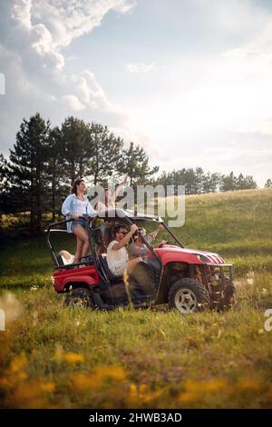 Jeunes heureux heureux heureux amis appréciant une belle journée ensoleillée tout en conduisant une voiture hors route buggy sur la nature de montagne. Liberté, amitié, concept de la nature. Banque D'Images