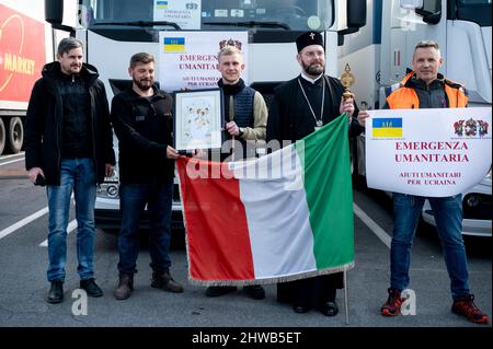 Milan, Italie. 04th mars 2022. Archevêque Avondios (2R) vu avec des camionneurs, portant un drapeau italien, l'icône de la Vierge Marie et l'écriteau 'urgence humanitaire'. Près de 15 véhicules, transportant de l'aide humanitaire, organisés par l'église orthodoxe de San Nicola et Ambrogio al Lazzaretto à Milan, partent le 4th mars pour apporter des vêtements, de la nourriture et des nécessités à des personnes en Ukraine, traversant la Roumanie. L'archevêque Avondios Bica dirige le convoi jusqu'à Chernivtsi, en Ukraine. Crédit : SOPA Images Limited/Alamy Live News Banque D'Images