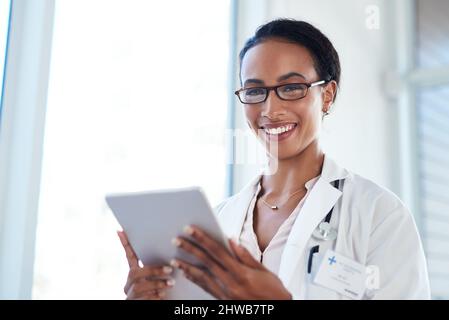 Rester au courant des progrès médicaux. Prise de vue d'un jeune médecin utilisant une tablette numérique dans sa salle de consultation. Banque D'Images