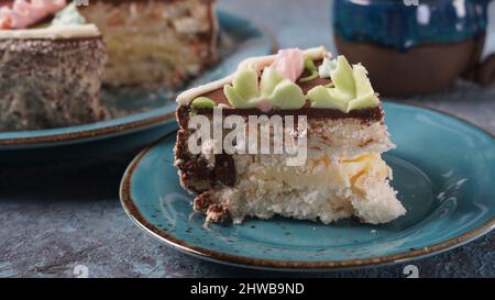 Morceau de gâteau de Kiev à la crème au chocolat et décoré sur une assiette bleue Banque D'Images