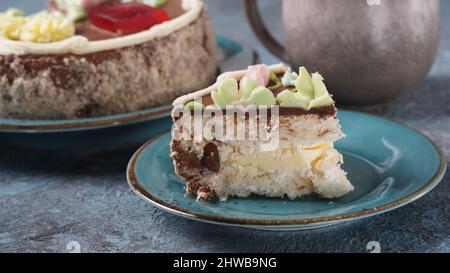 Morceau de gâteau de Kiev à la crème au chocolat et décoré sur une assiette bleue Banque D'Images