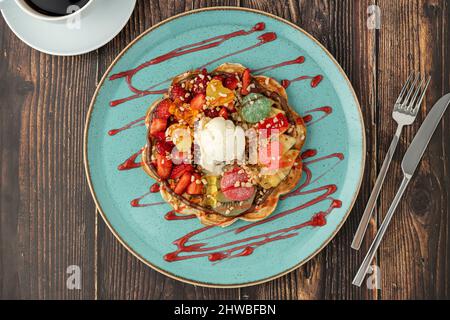 Gaufre de coeur avec banane et fraise avec bonbons délicieux et glace sur elle. Banque D'Images